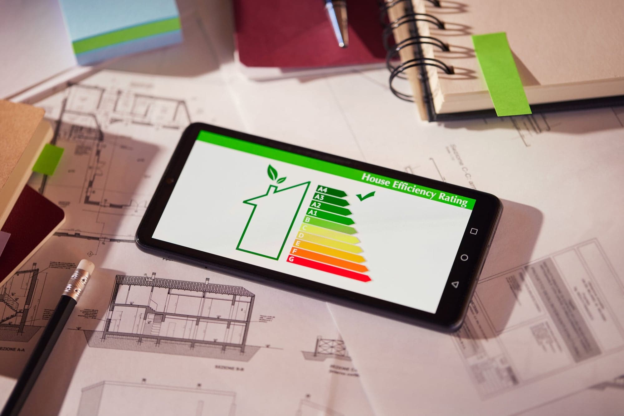 Energy performance certificate and efficiency classes on a smartphone next to building plans, energy consulting for buildings in Wiesbaden